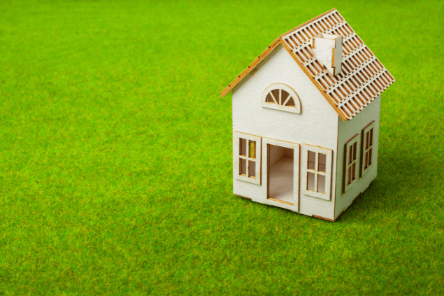Uma casa em miniatura em cima de um gramado verde