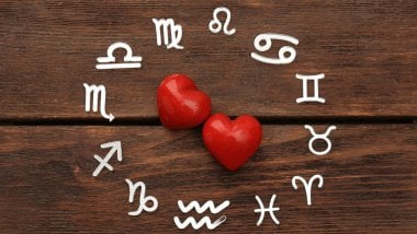 Há uma Roda do Zodíaco com os símbolos dos signos em volta. No meio, há dois corações.