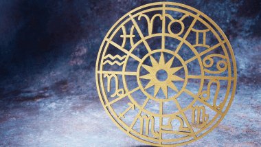 No foco da imagem, há uma Roda do Zodíaco na cor dourada.