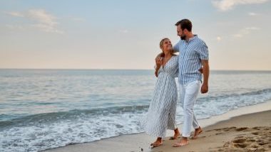 Imagem de um casal caminhando na beira da praia.