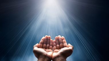 Imagem das mãos erguidas sob um feixe de luz, simbolizando a fé e a espiritualidade.