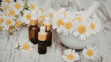 Imagem de três vidros com frorais sobre uma mesa de madeira branca decorada com margaridas e um macerador com pistilo para flores.