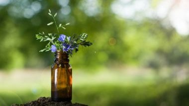 Imagem de um pequeno vidro com óleo essencial e flores na cor lilás.