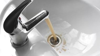 Água suja corrente saindo de uma torneira da pia.