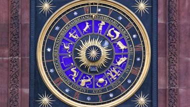 Imagem de um relógio de parede com o formato de uma mandala astrológica nas cores azul escuro e azul claro, dourado e vinho.