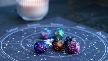 Imagem de uma mandala astrológica na cor azul e sobre ela, várias pedras coloridas com os glifos dos signos.