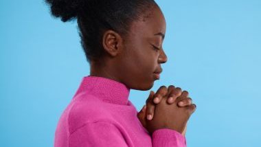 Imagem de uma mulher preta com uma blusa rosa em oração.