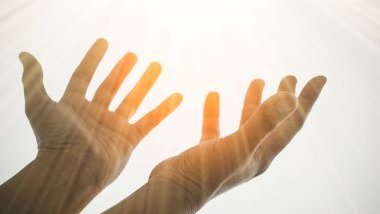 Imagem das mãos de um homem levantadas para o céu em sinal de oração.