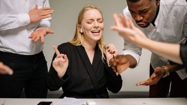 Imagem de um grupo de homens e mulheres discutindo sobre alguma questão profissional. A foto simboliza uma briga, uma discussão de negócios.