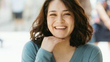 Imagem de um mulher de cabelos castanhos e curtos sorrindo muito.