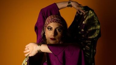 Imagem de uma cigana usando uma blusa roxa com um lenço dourado nas costas.