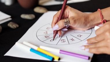 Imagem das mãos de uma astróloga desenhando uma mandala astrológica.