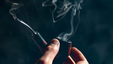 Imagem de uma mão masculina segurando um cachimbo. A imagem traz o conceito do preto-velho Pai Joaquim de Angola na Umbanda.