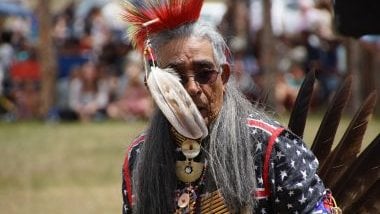 Imagem de um homem com um cocar vermelhoe uma pena branca, simbolizando o caboclo Pena Vermelha da Umbanda.