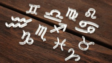 Os símbolos dos signos do zodíaco estão espalhados sobre uma superfície de madeira.
