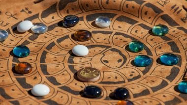 Imagem de uma mandala astrológica e sobre ela, várias pedras de cristais.