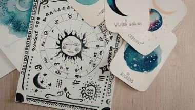Imagem de algumas cartas dos signos sobre uma mesa de madeira na cor bege.