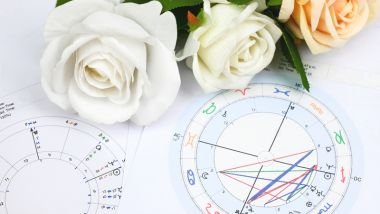 Imagem do desenho de um mapa astral e sobre ele, botões de rosas brancas e amarelas.