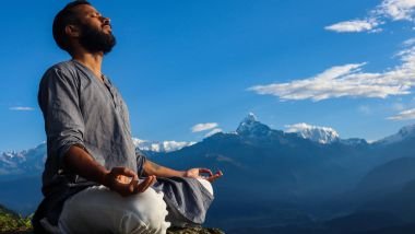 Imagem de um homem meditando sobre uma pedra e ao fundo uma montanha e o céu com nuvens.