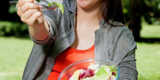 Mulher oferecendo um garfo de salada