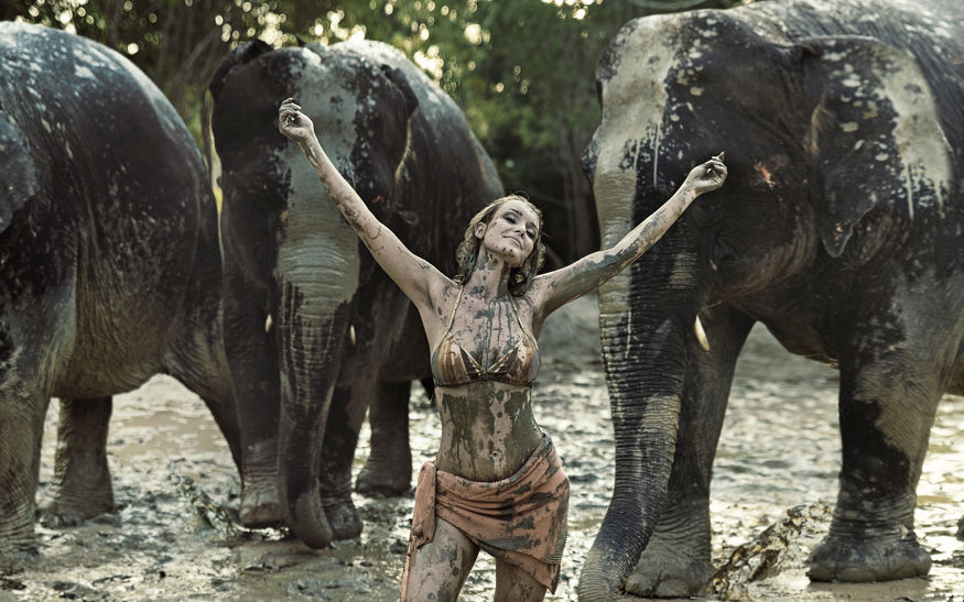 Mulher coberta de lama com elefantes