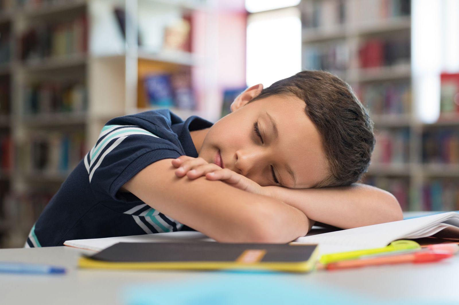 Criança dormindo na carteira da sala de aula