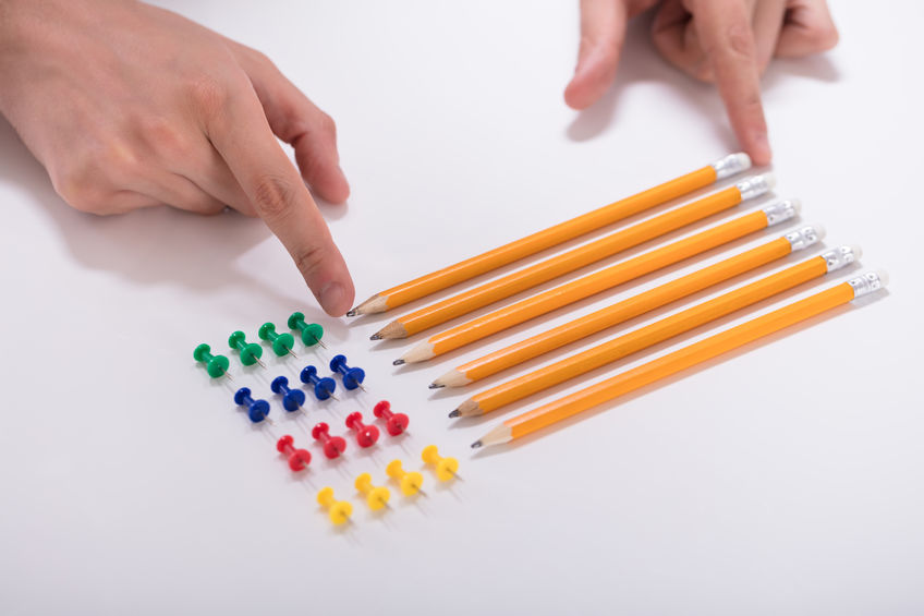 Mãos brancos arrumando lápis amarelos.