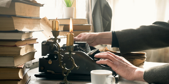 Escritor sentado na sua mesa escrevendo em máquina de datilografia