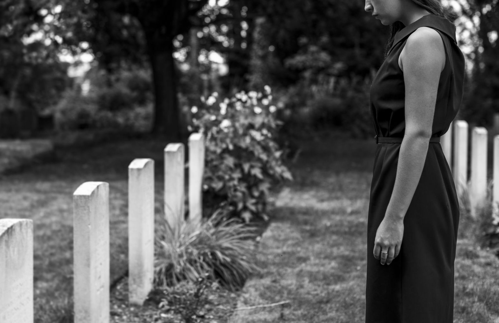 Mulher em frente a uma lápide no cemitério 