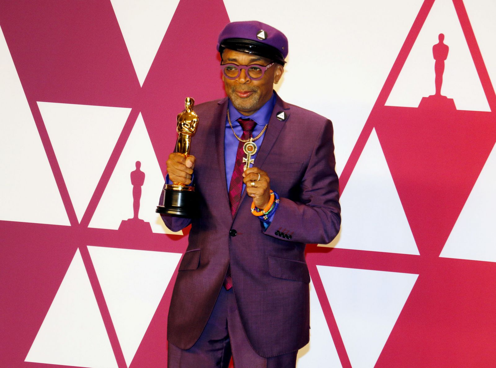Spike Lee olhando para frente sorrindo e com suas mãos segurando premiação do Oscar