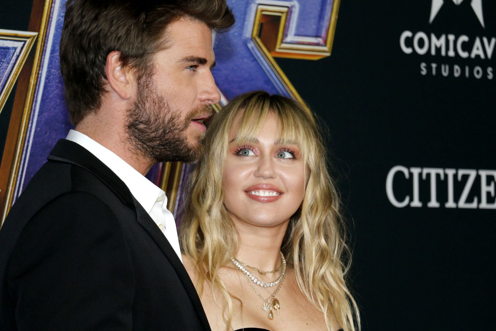 Miley Cyrus ao lado de seu namorado sorrindo em premiação