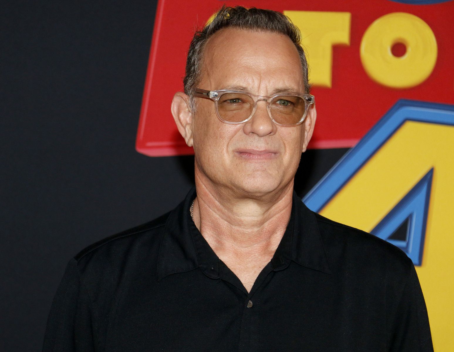 Tom Hanks sorrindo de óculos em uma premiação do filme Toy Story