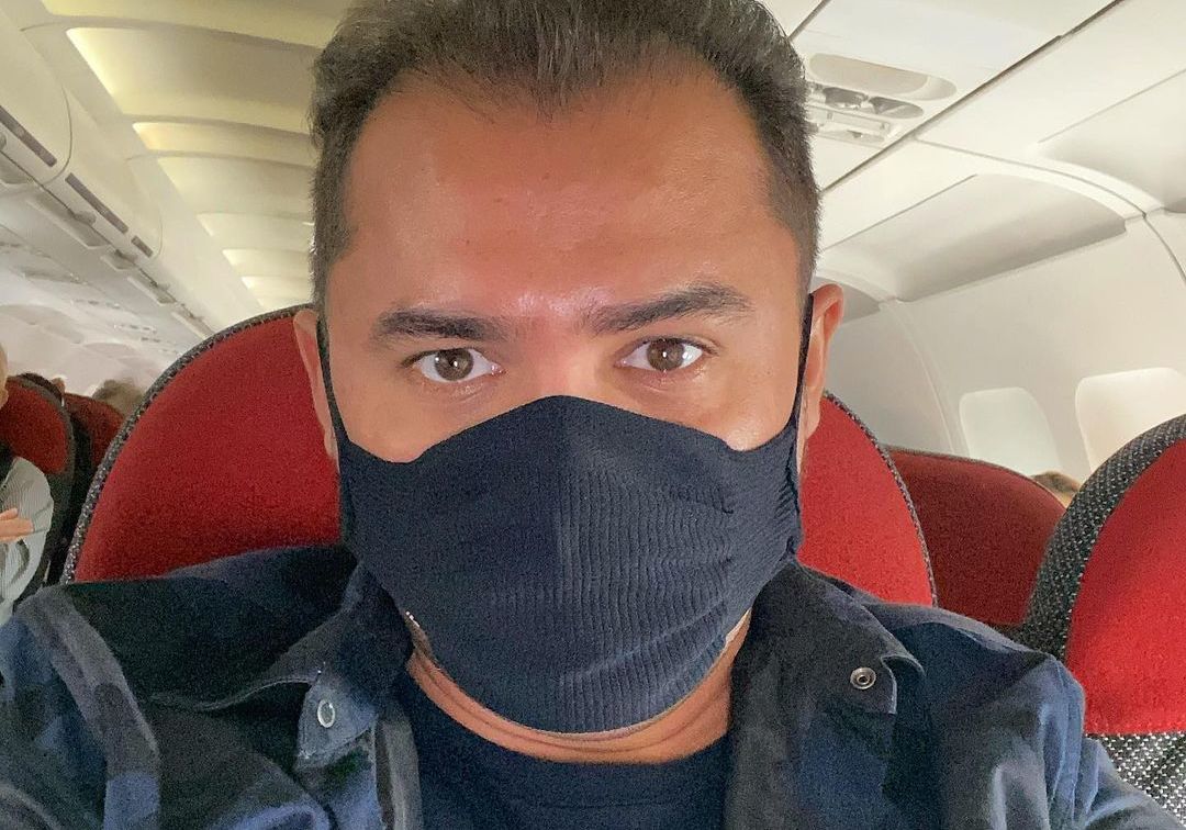 Homem branco usando máscara num avião.