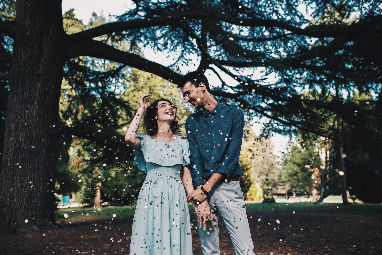 Home e mulher de mãos dadas em um parque com confete caindo