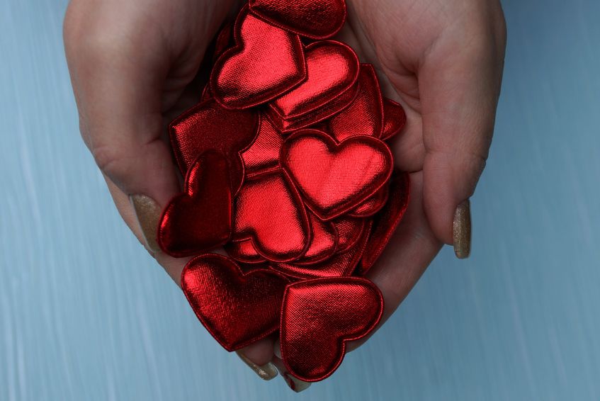 Pessoa segurando recortes em formato de coração 