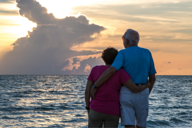 casal idoso se abraçando na praia assistindo ao pôr do sol