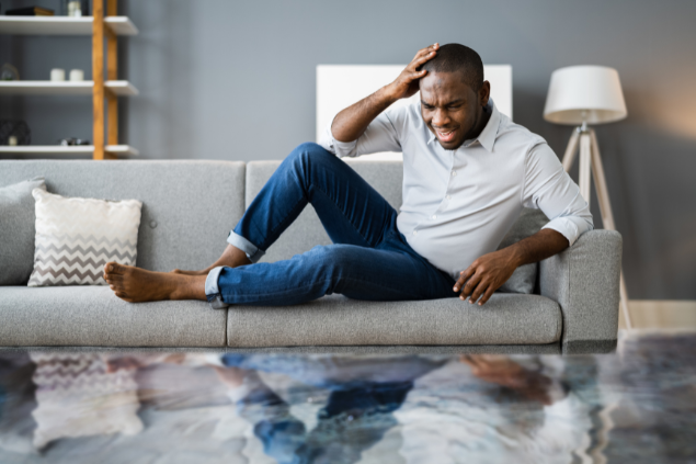 Homem negro em cima do sofá em meio a inundação.