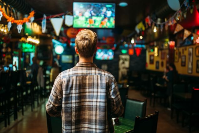 Homem assistindo um jogo de futebol no bar