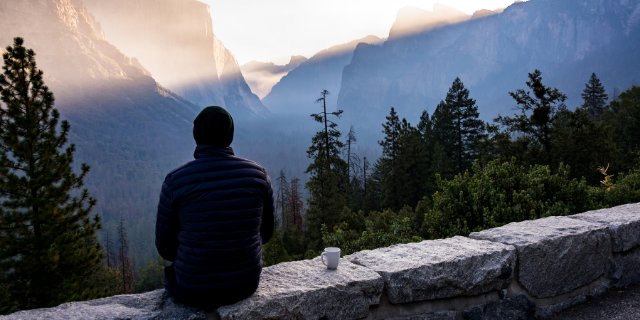 Homem sentado observando as montanhas