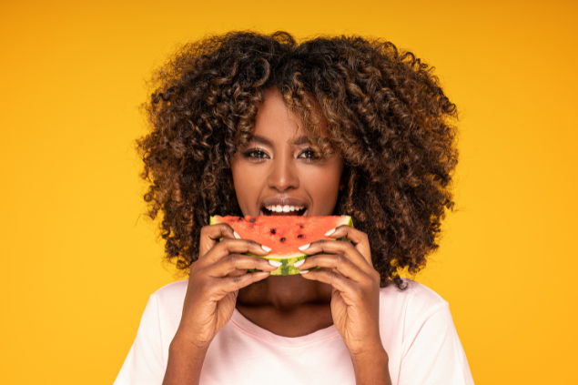 Mulher negra comendo pedaço de melancia