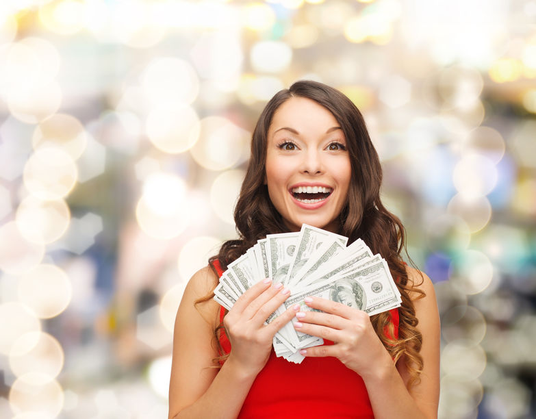 Mulher segurando cédulas de dinheiro e sorrindo