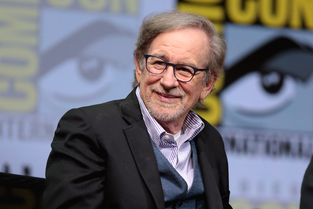 Steven Spielberg de óculos sorrindo e olhando para o lado