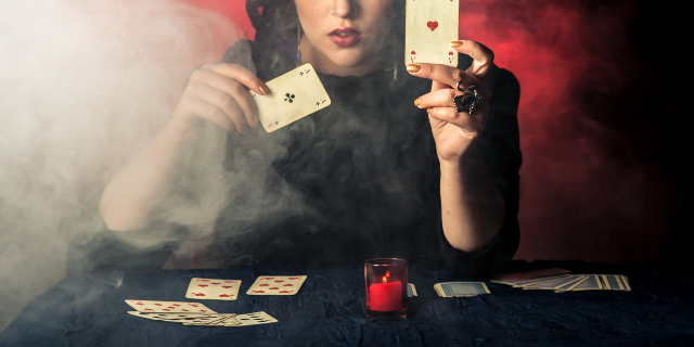 Mulher cigana em mesa de previsões segurando um baralho