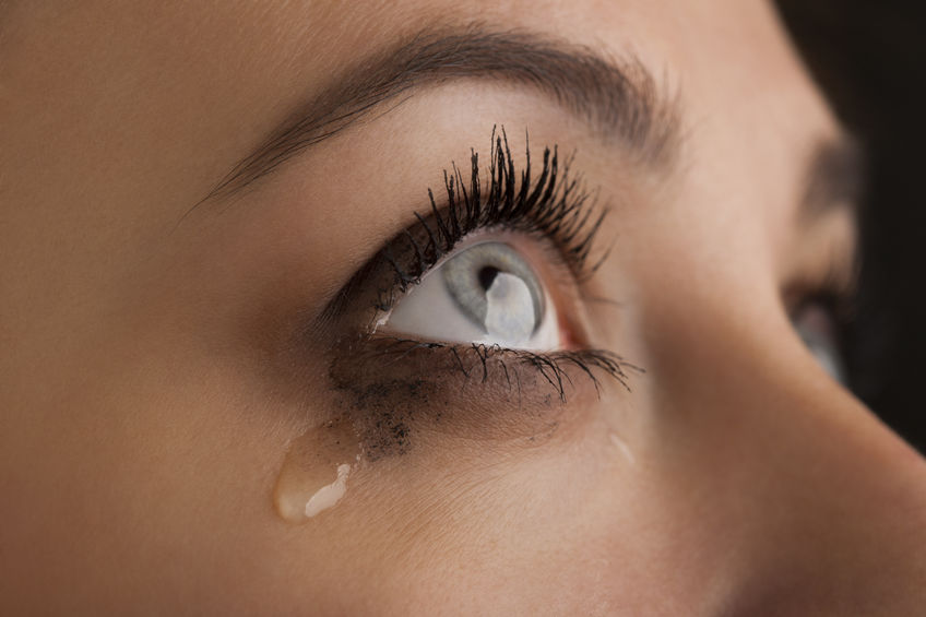 Olhos de mulher chorando, com maquiagem preta escorrendo com as lágrimas.