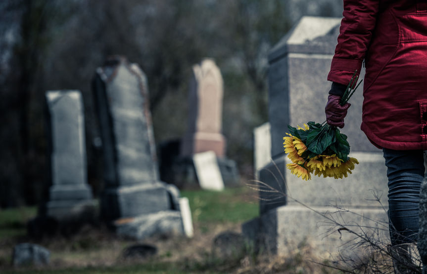 Pessoa em um cemitério em frente a uma lápide