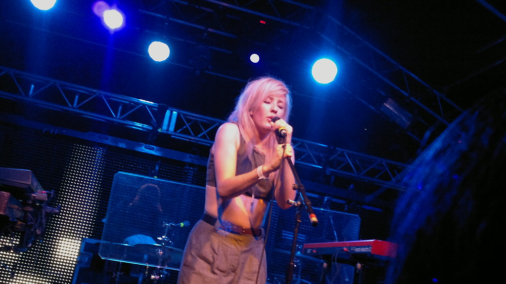 Ellie Goulding com os olhos fechados cantando no palco