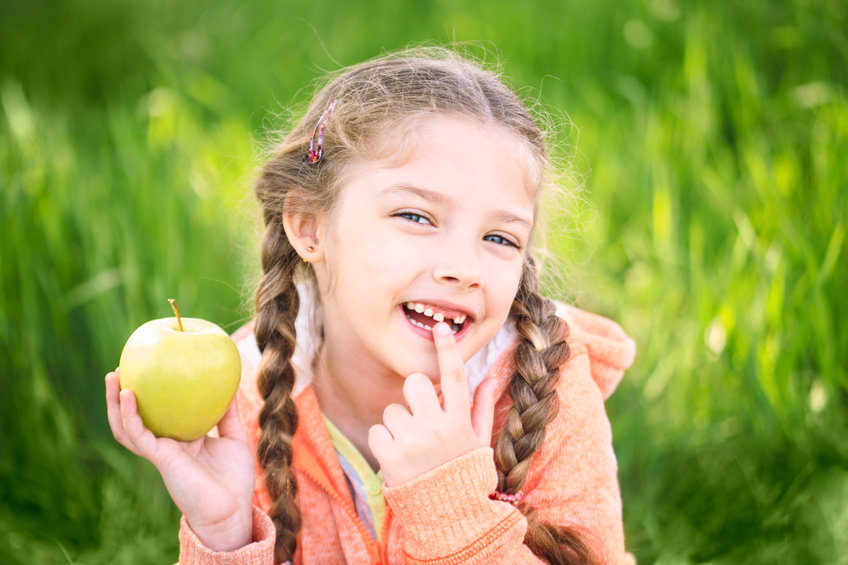Criança branca segurando maçã.