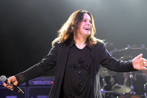 Ozzy Osbourne sorrindo no palco segurando microfone