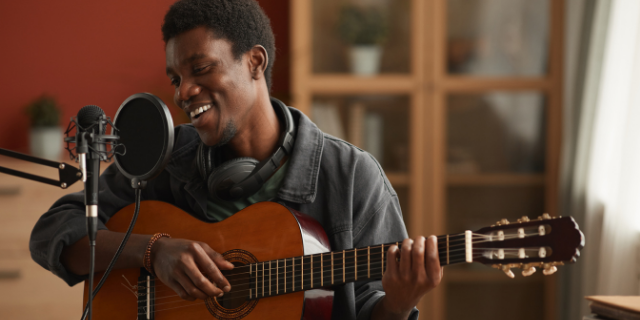 Homem feliz tocando violão e cantando em casa