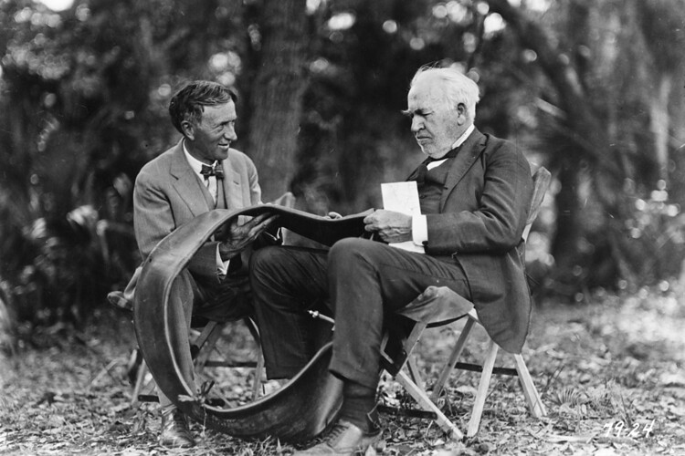 Thomas Edison sentado em uma cadeira ao lado de um homem